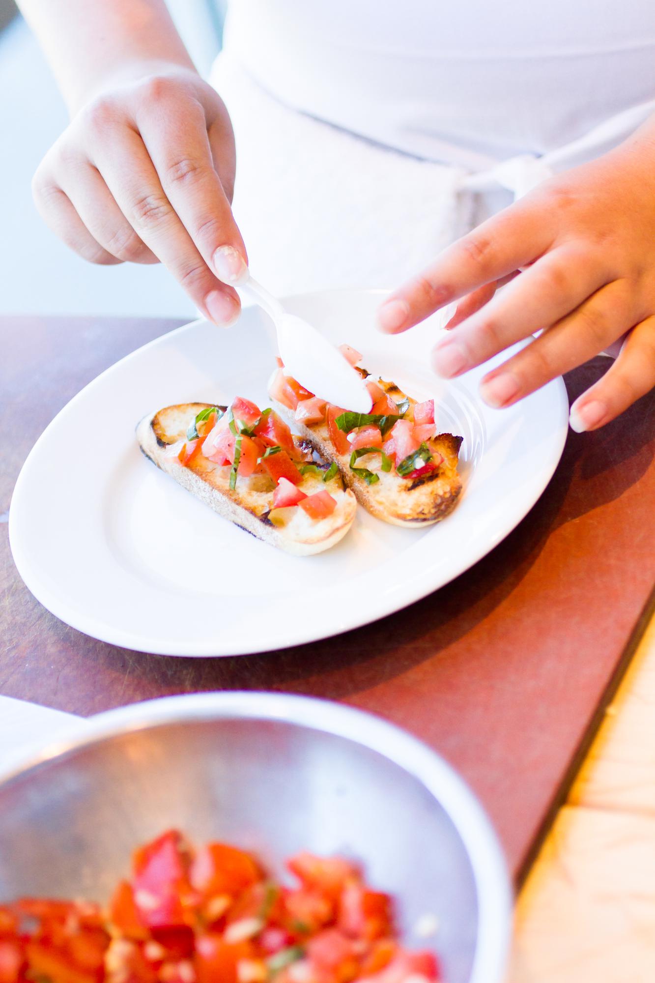 Close-up of hands seasoning a composed plate